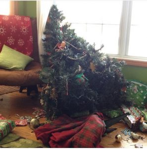 Christmas tree that has crashed to the floor, laying amongstt gifts and broken ornaments
