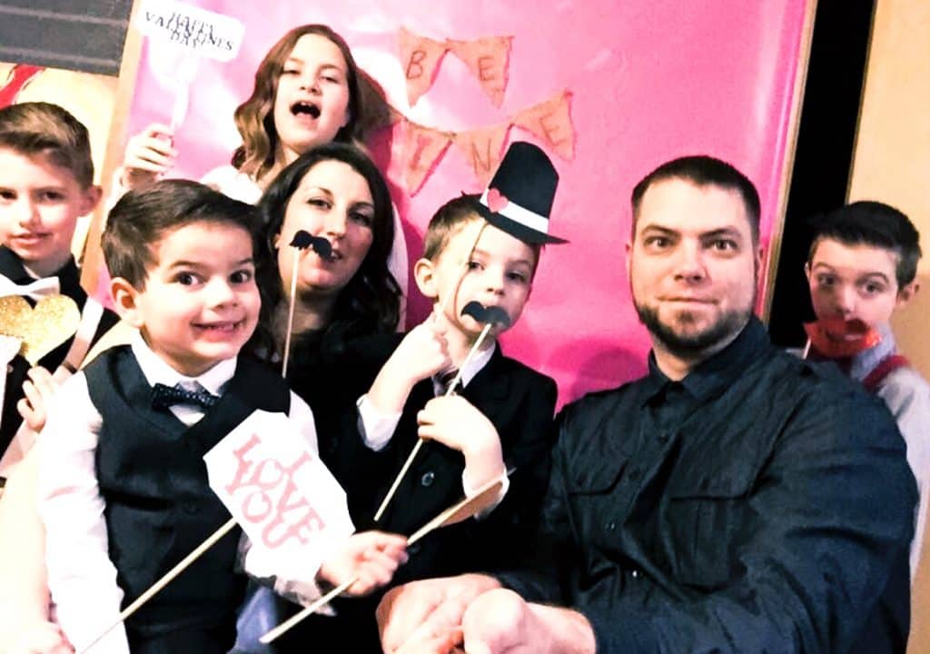 Family of 7 holding Valentine photo props and celebrating a Valentine's Day Family Night
