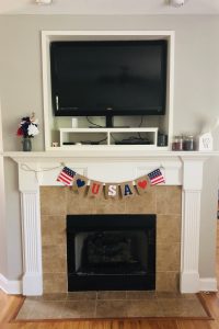 patriotic mantle decor with USA banner and red, white, and blue flowers