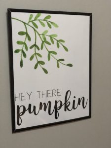 fall wall art printable that reads "hey there, pumpkin" with some greenery in the background