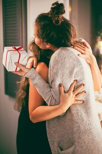 Friend giving gift hugging