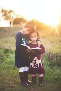 two young girls reading the Bible together