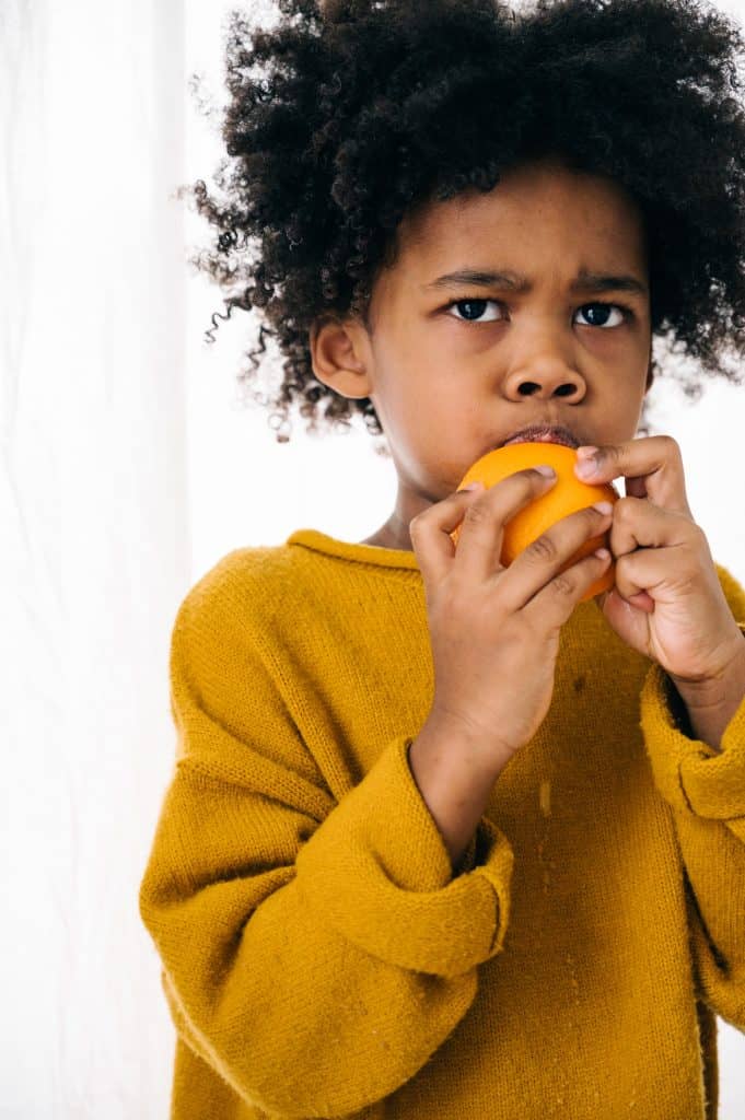 child eating a piece of fruit