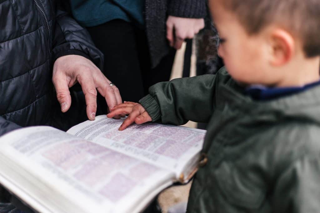 child pointing to scripture in the Bible