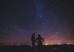 A couple camping looking at a starry night sky enjoying God's creation.