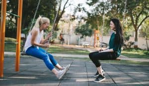 Best friends swinging together chatting