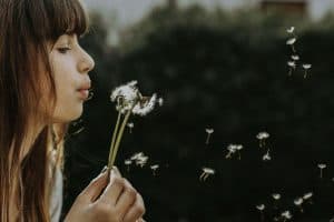 Girl blowing a dandilion in the air