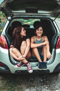 Best friends chatting together in the back of a car.