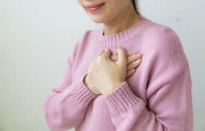 Woman in pink sweater with her hands on her heart