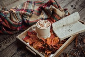 Hot chocolate, plaid blanket, and a book on a fall day