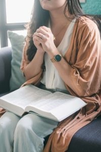 woman praying with her bible, asking God to help her set spiritual goals for the new year