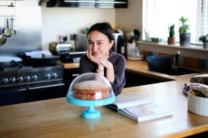 Homemaker in kitchen with a baked cake.