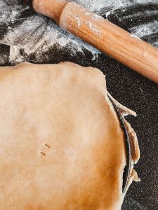 homemade pie crust next to a rolling pin