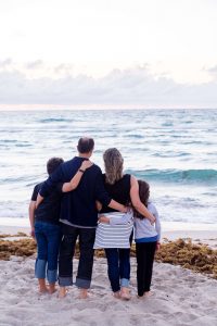 strong Christian family of four staring out at the ocean