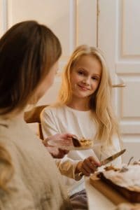 Mom serving a piece of pie to her daughter, who looks grateful