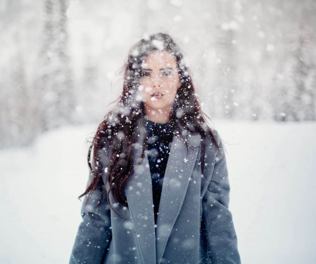 woman standing in a flurry of snow