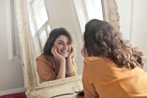 woman looking into a mirror, smiling