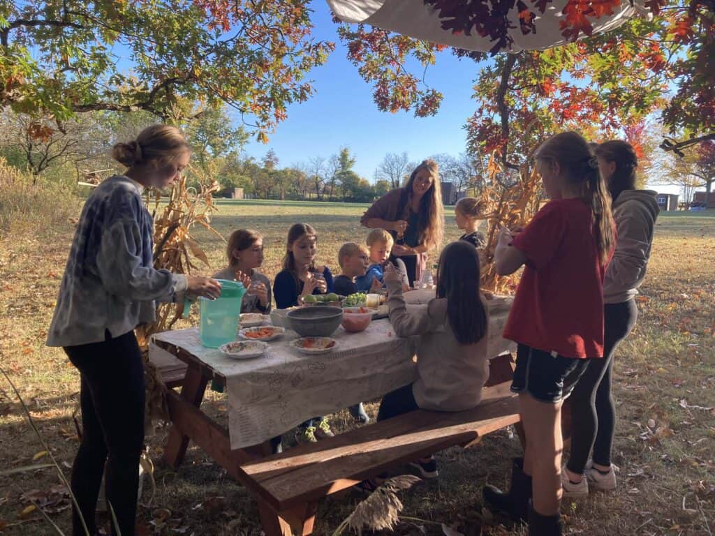 Kids sitting at a picnic table outside in a temporary dwelling for Feast of Tabernacles