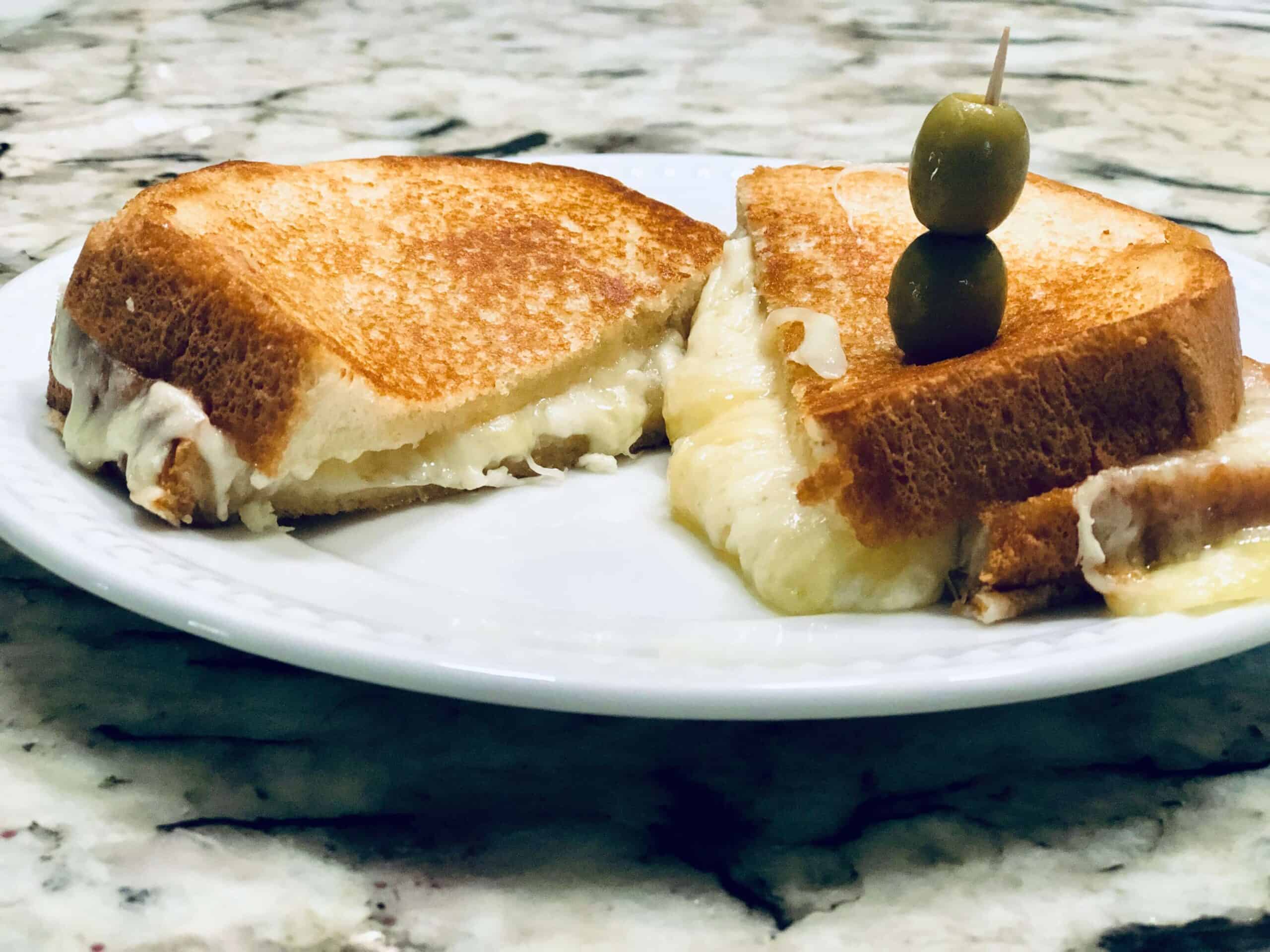 Asiago Grilled Cheese on a plate topped with olives
