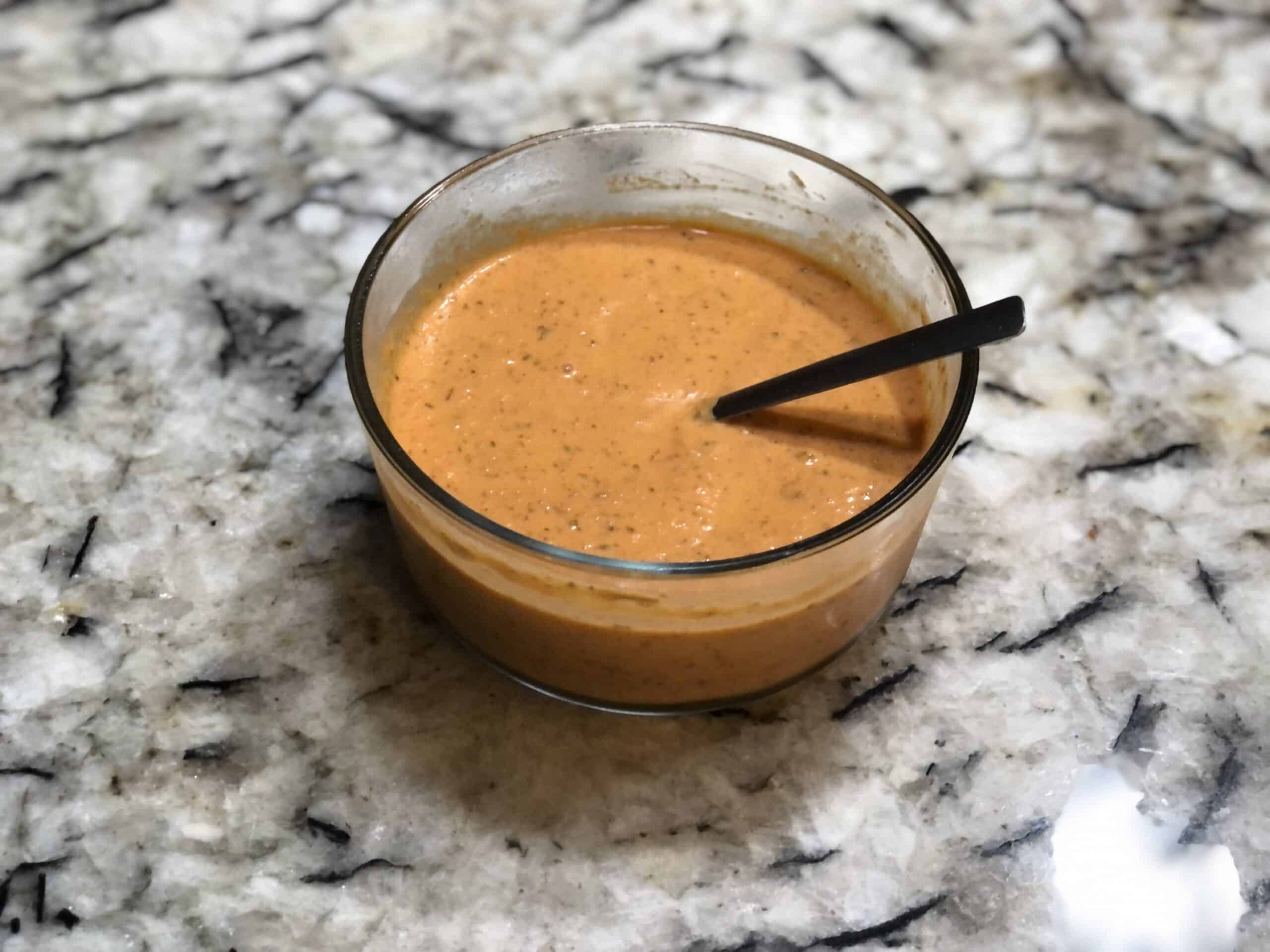 spicy creamy tomato soup in a glass bowl on a granite counter