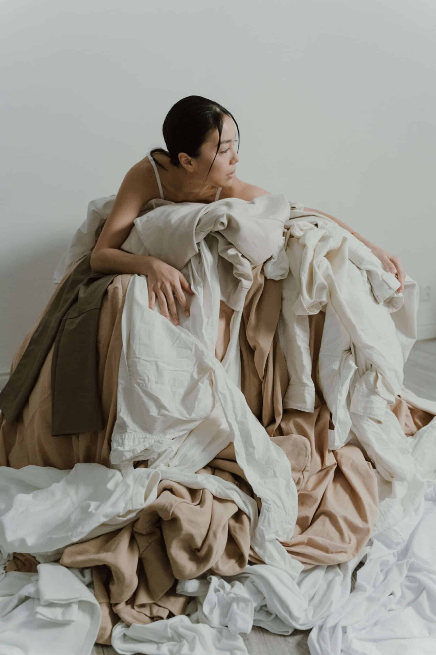 Woman laying on top of a pile of clothes, from the blog post, "How to keep on top of laundry"