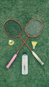 badminton rackets and birdie laying on grass
