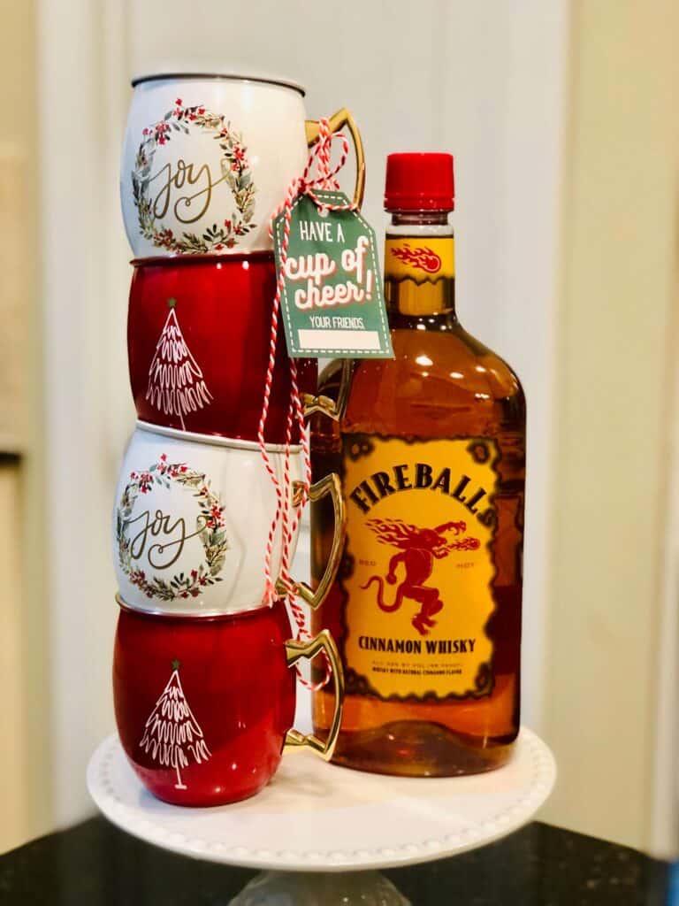 Christmas Moscow mule mugs and bottle of fireball with Doorbell Ditch Christmas gift tag from Just Homemaking: "Have a cup of cheer!"
