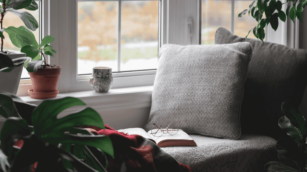 How to be a happy homemaker: create a home you love to live in. Pillow and book next to window.