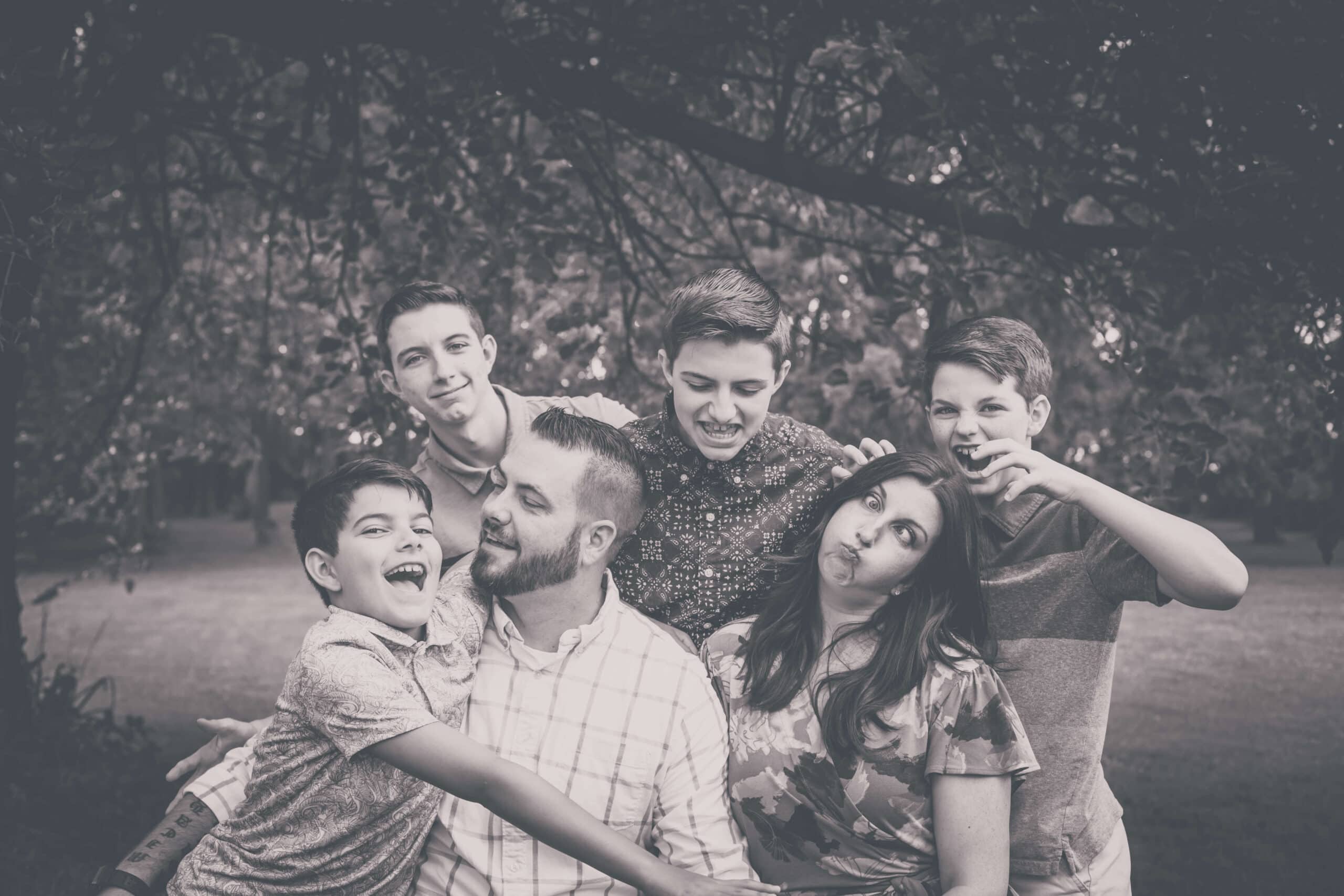 What no one tells you about raising teen boys: Mom and Dad with their four teenage boys making a silly-face picture