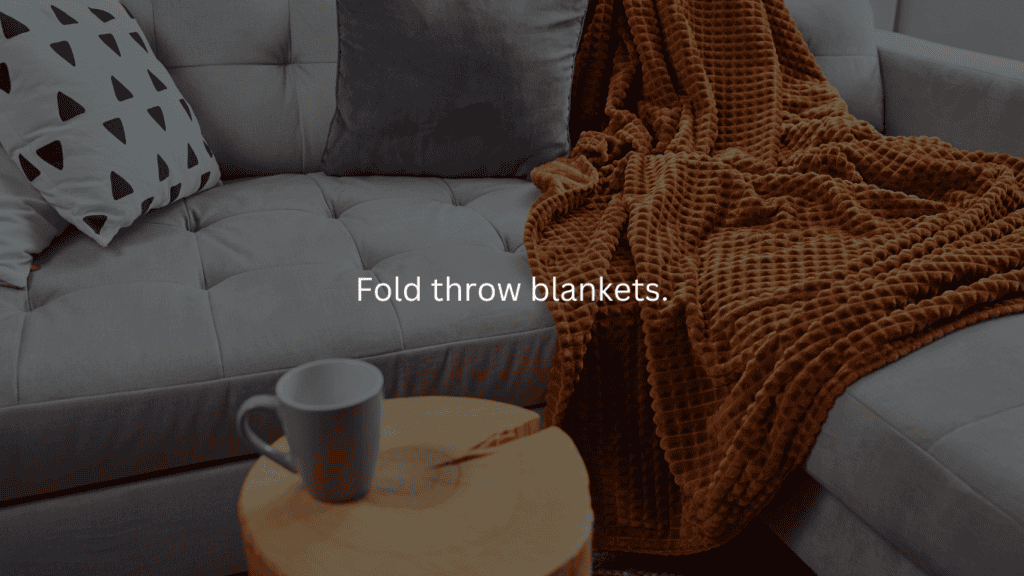 Nightly cleaning routine: fold throw blankets. Couch with throw blanket, small table with a mug of coffee.